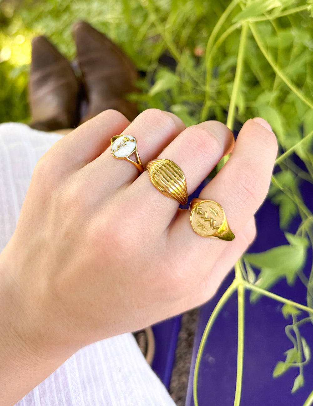 Gold-tone signet ring with engraved face motif on finger