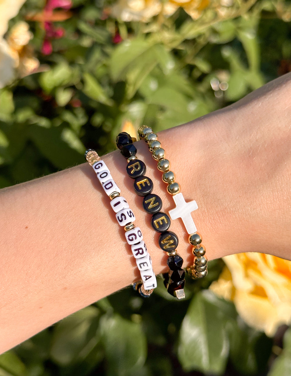 Multicolor beaded bracelet with white cross charm on wrist