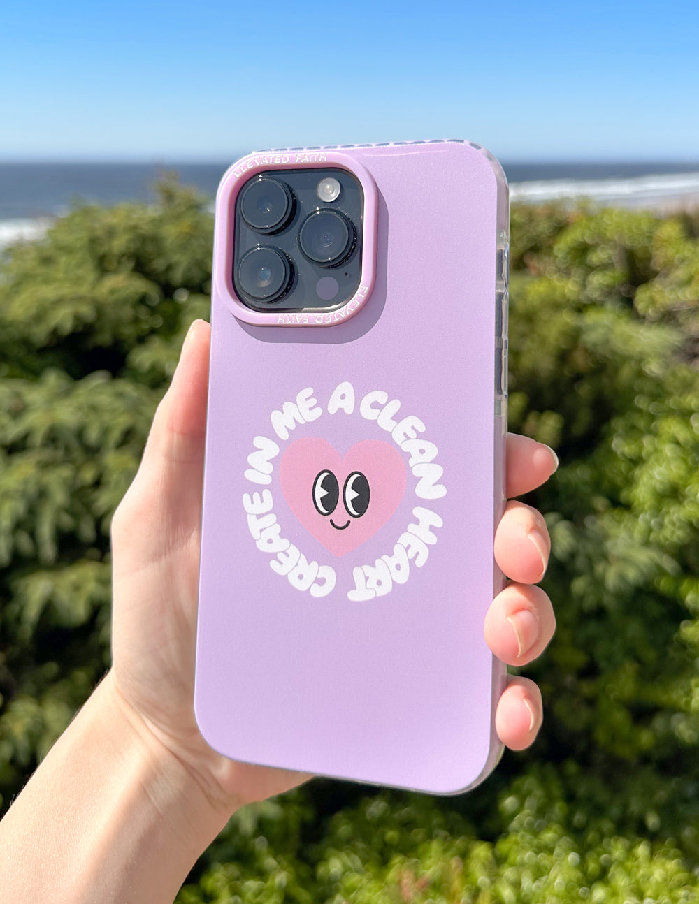 Lilac phone case with alien-face graphic and arched text, held in hand