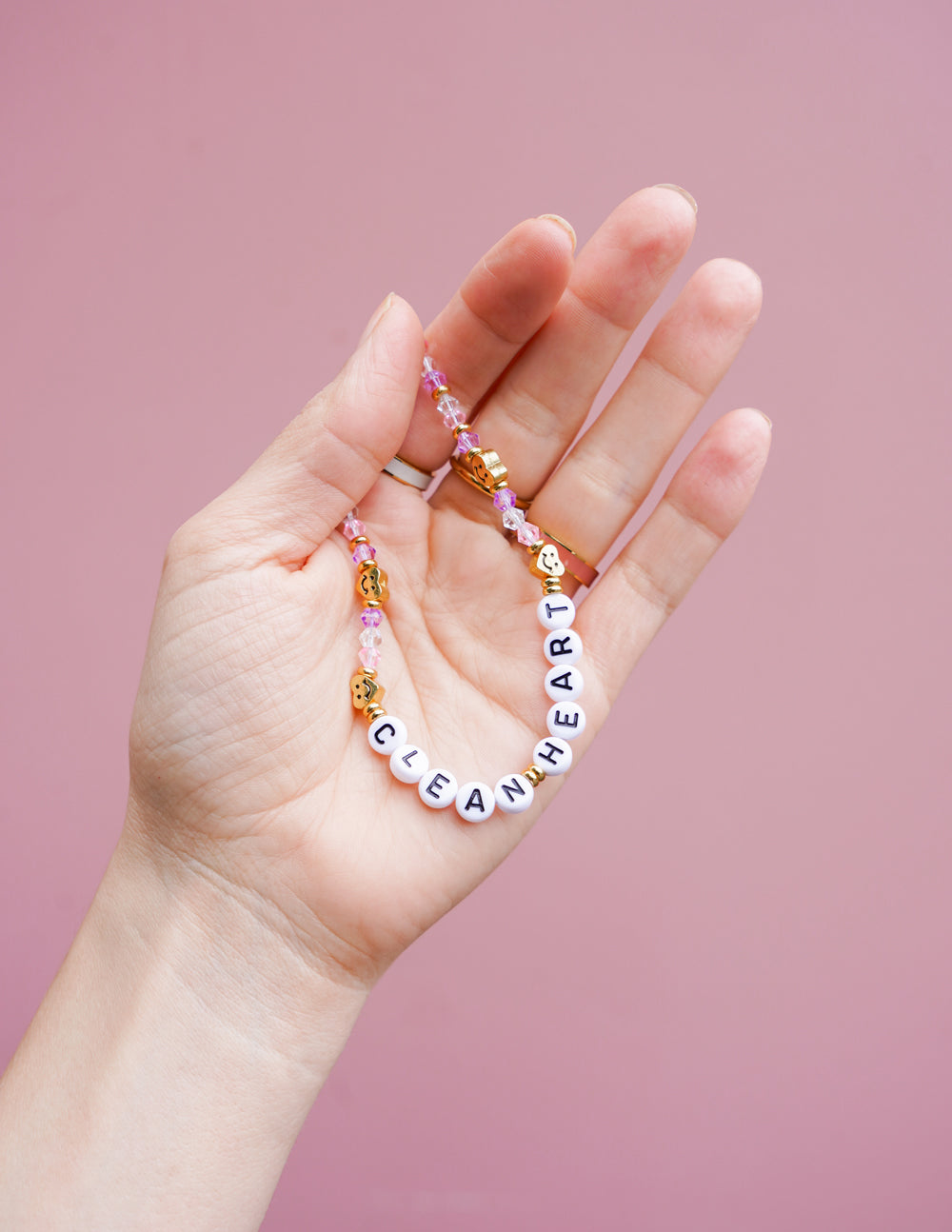Beaded heart phone charm with white letter beads and gold round accents on hand