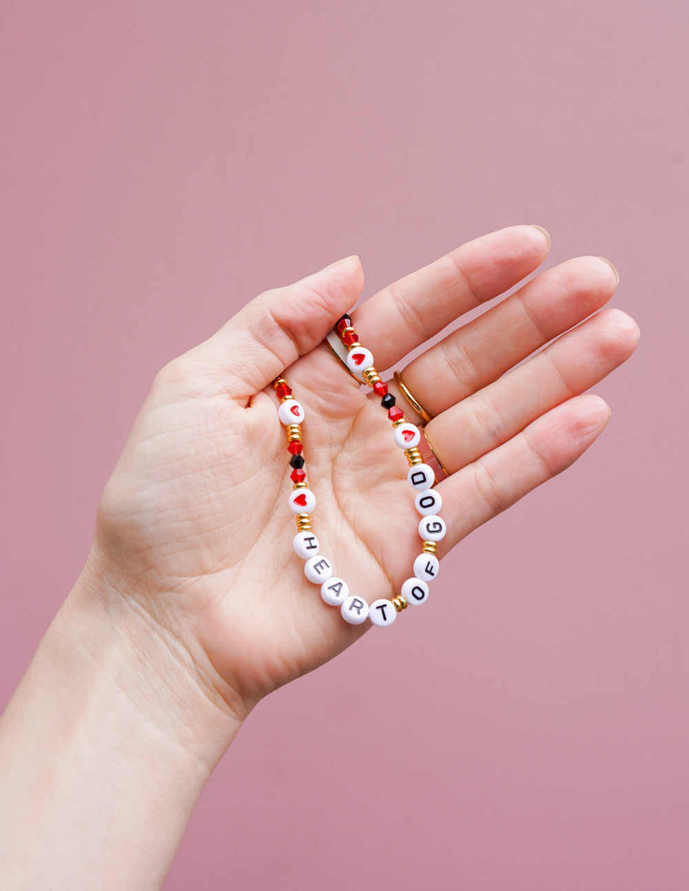 Beaded phone charm held in hand, red and white beads with letter beads