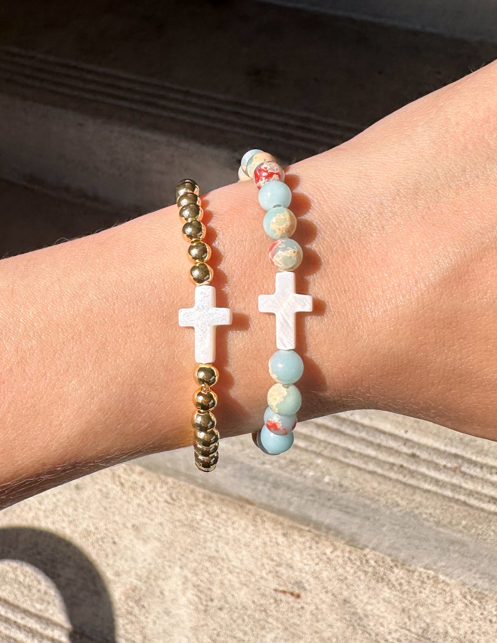 Beaded bracelet with two white cross charms and blue, red, and gold beads