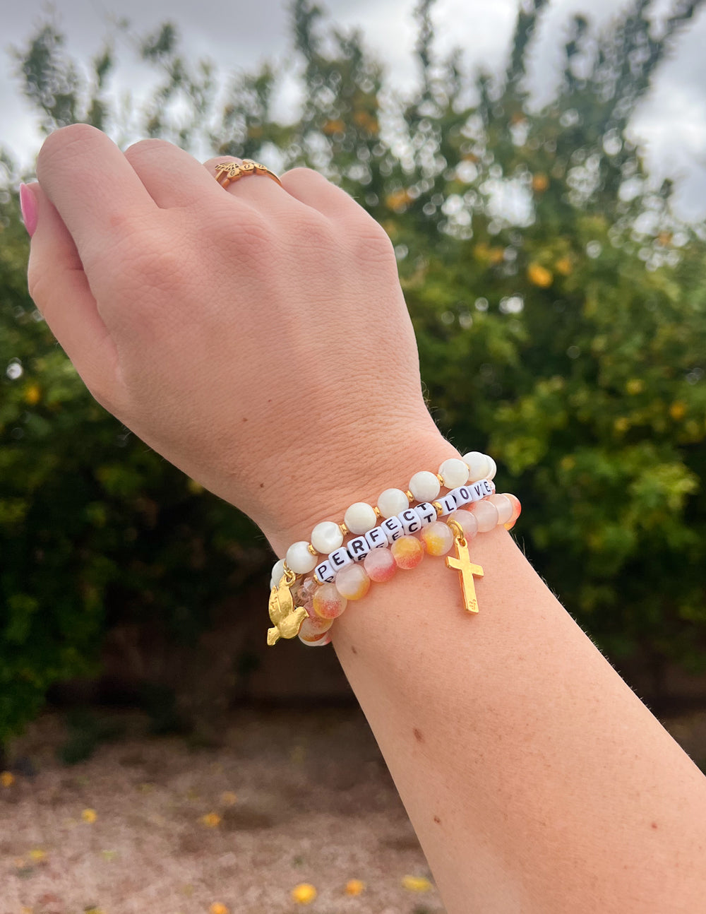 Beaded bracelet set with white beads and gold cross charm, lettering on beads