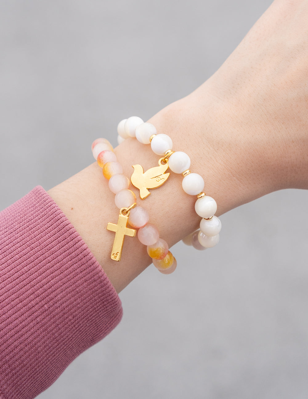 White and peach beaded bracelet with gold cross and bird charms