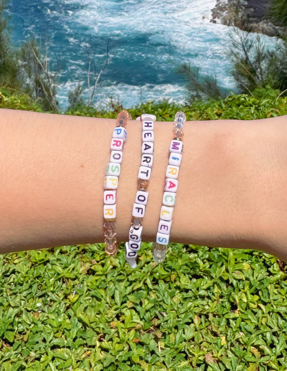 Beaded letter bracelets on wrists with blue and pink letter beads and elastic bands