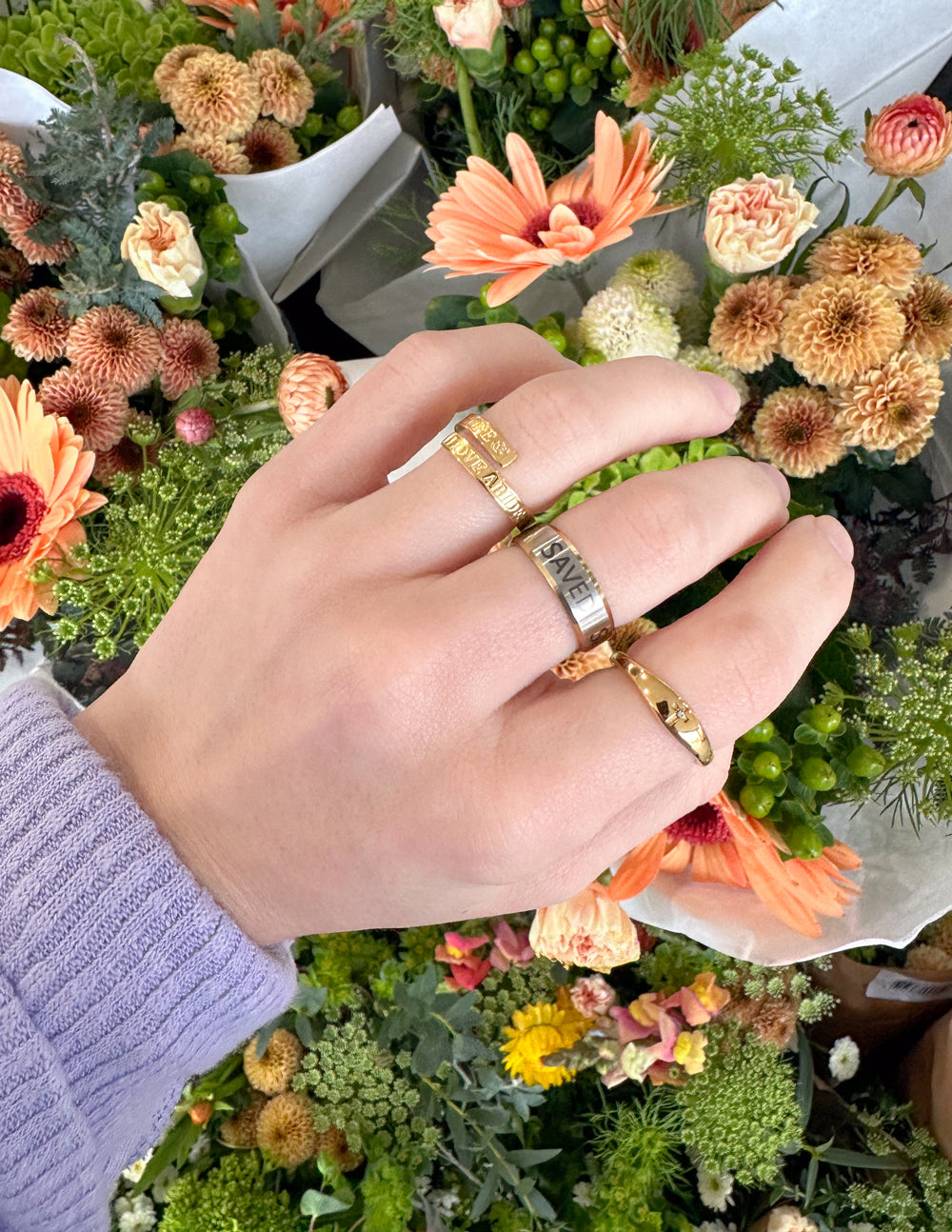 Gold-tone engraved rings on hand, three-band stack with small centerpiece