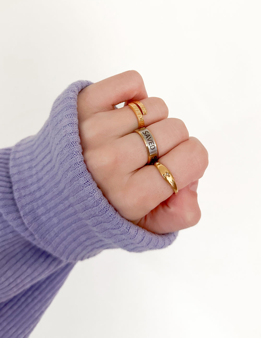 Gold-tone cross gemstone ring on finger, cross charm with dark center stones