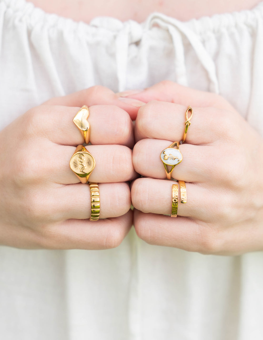 Gold spacer rings with charms on open palms, two-finger view