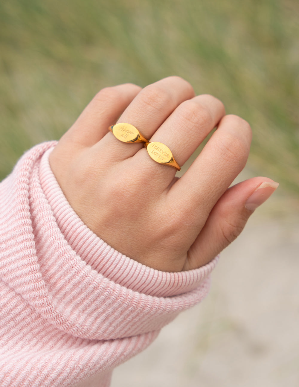 Gold oval signet ring with engraved script, worn on a finger
