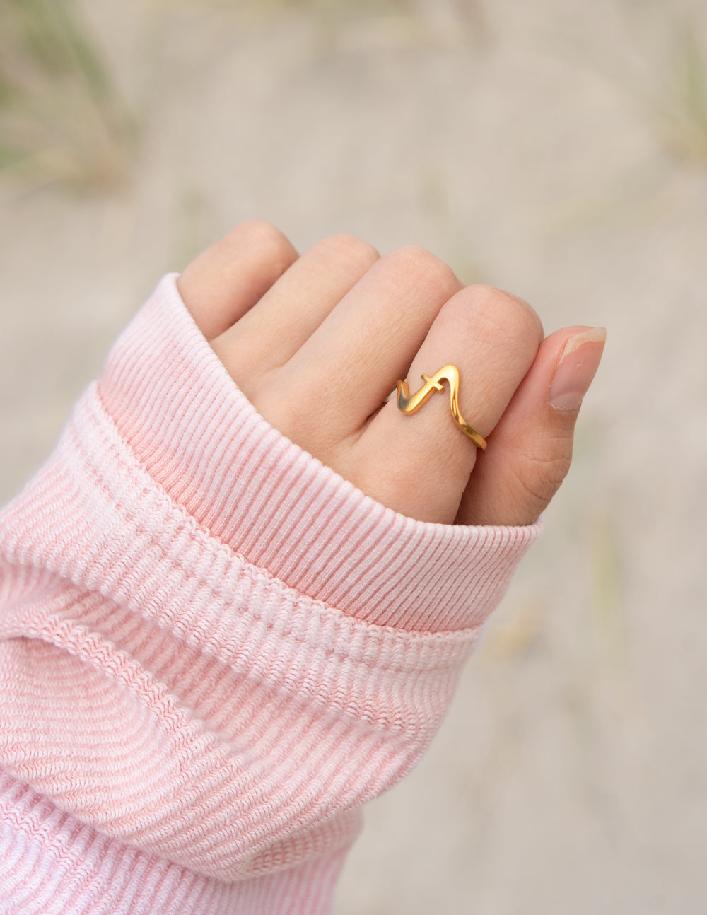 Gold wavy cross ring on finger, small cross detail on open band