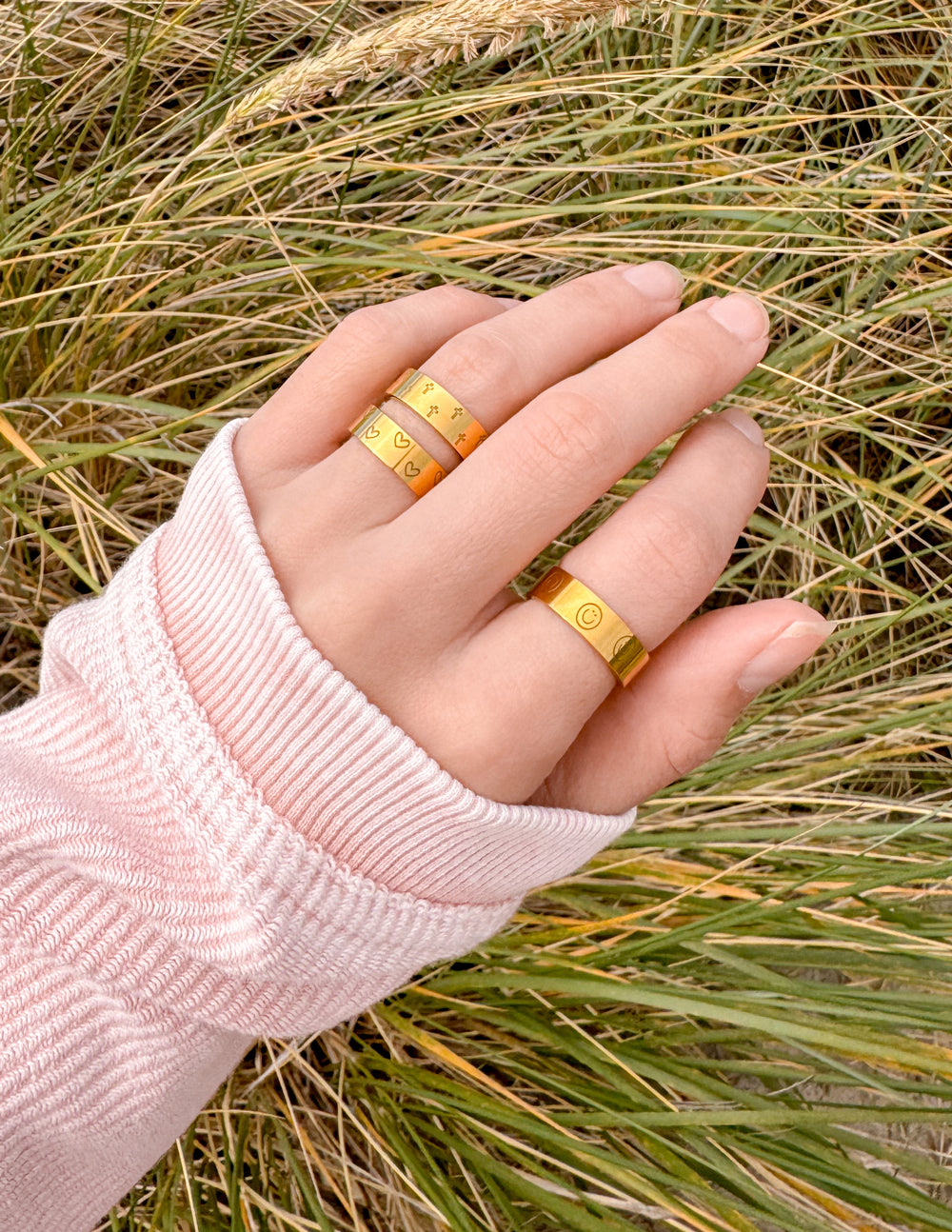 Gold-tone engraved ring set on hand, two slim bands with engraved icon patterns