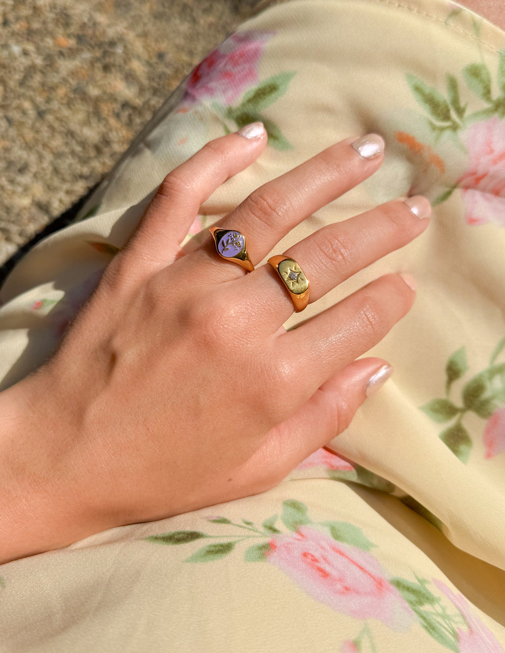 Gold signet ring with lavender flower enamel, worn on finger