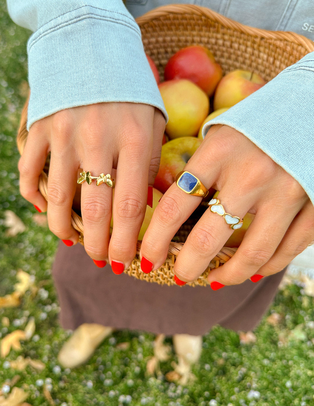 Gold butterfly motif ring with green stone center on finger