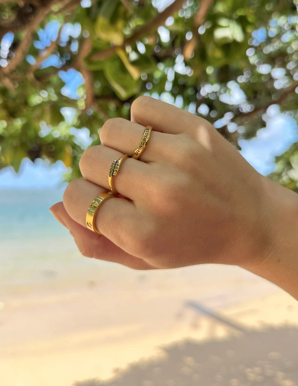 Gold ring with black 'CHOOSE JOY' text on the band, worn on finger