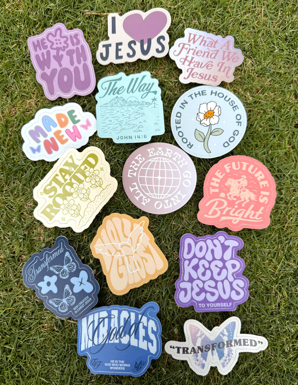 Religious stickers on grass with 'Jesus' text and earth-and-creation themed icons