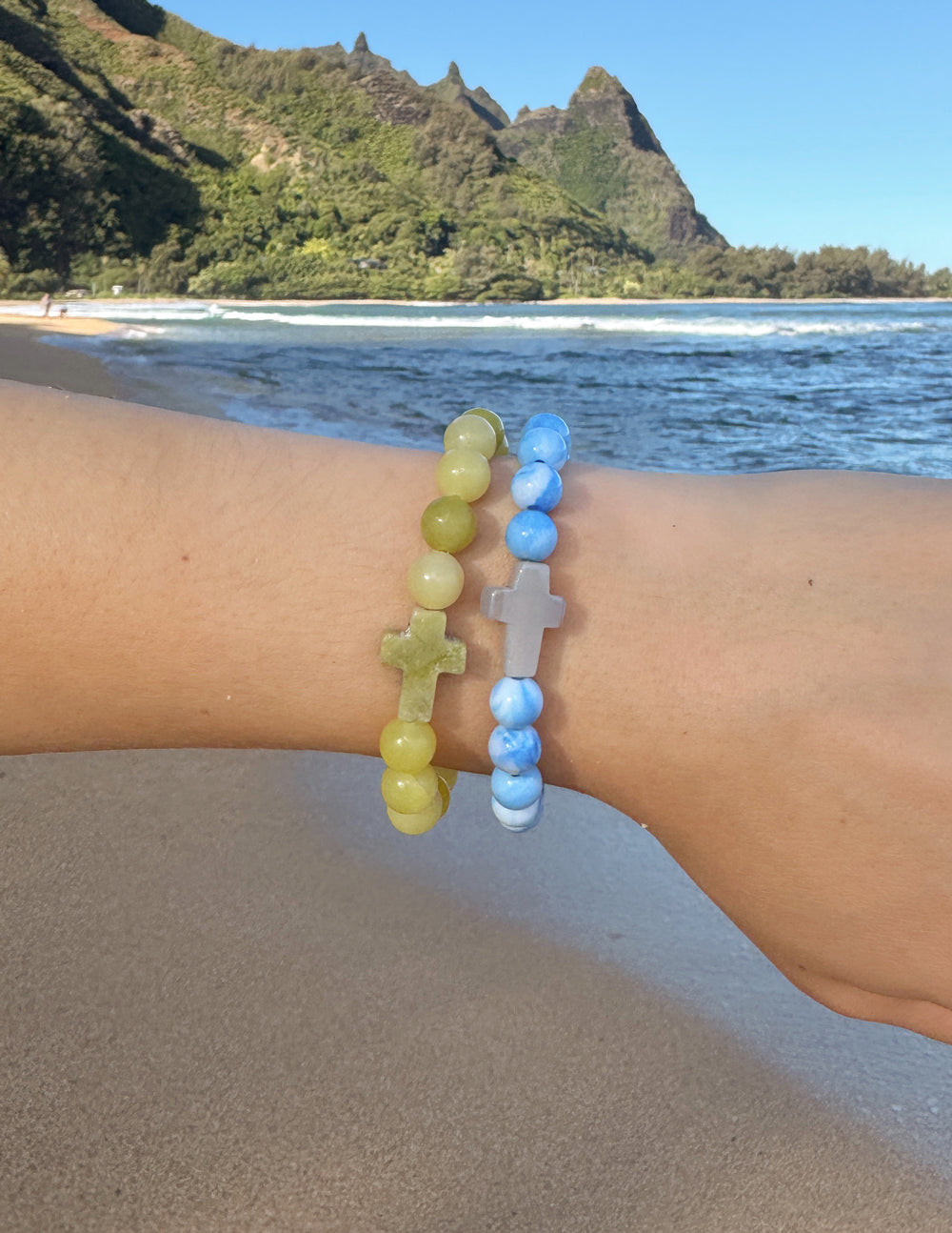 Stacked bracelets: light blue and yellow-green beads with matching cross charms