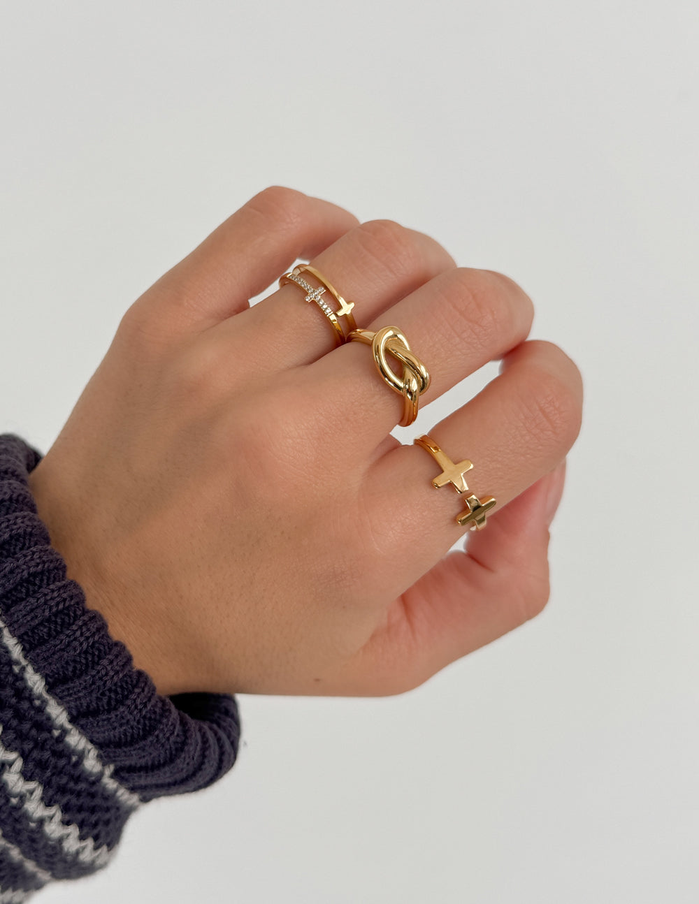 Gold-tone cross ring with chain-like detail and cross motifs, worn on finger