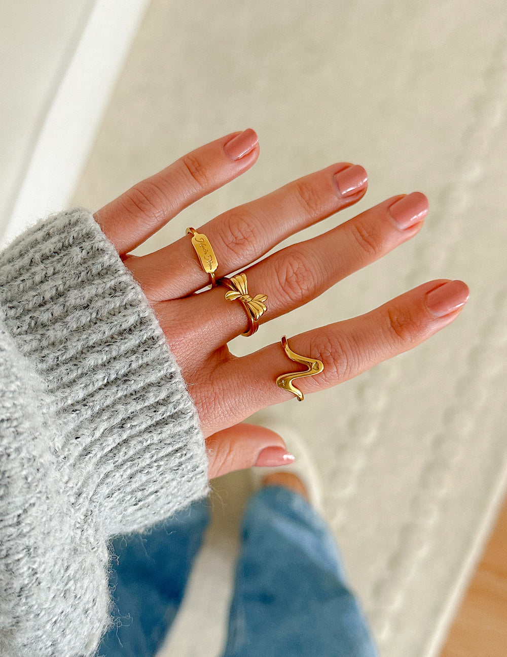 Gold ring set with engraved band and bow charm on hand