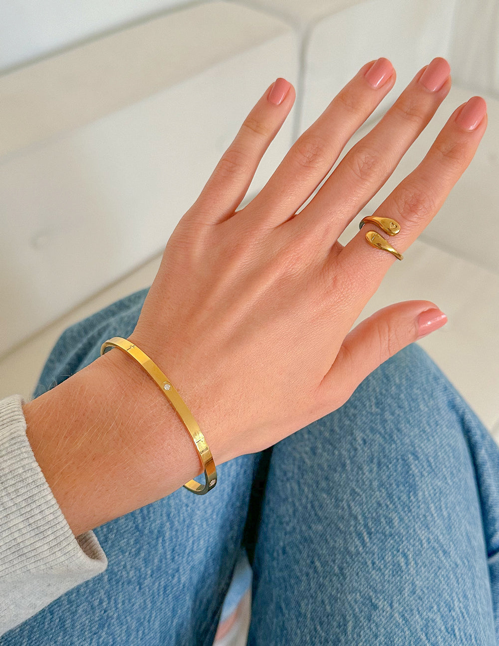 Gold-tone open ring on finger with heart and cross charms