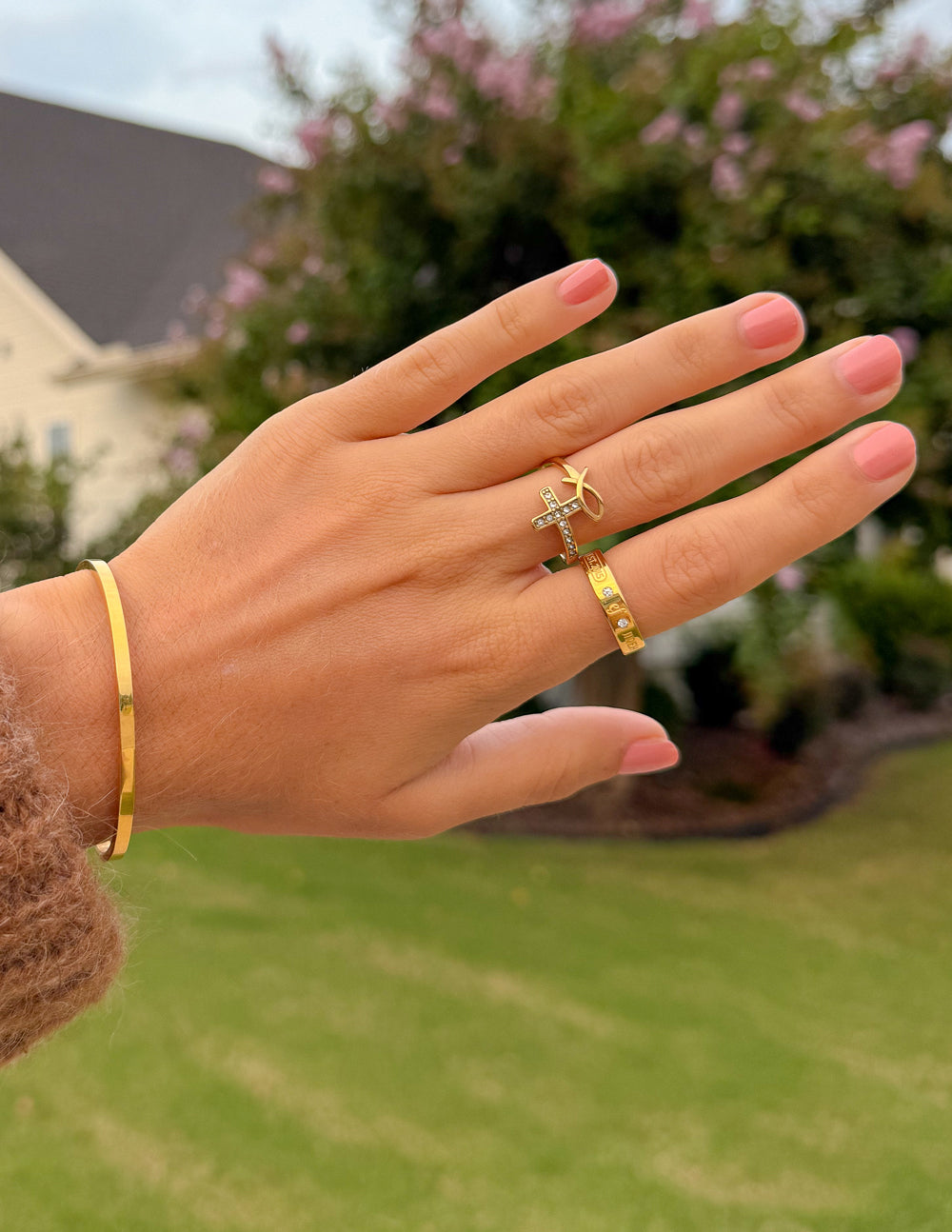 Gold cross cuff bracelet on wrist with cross charm