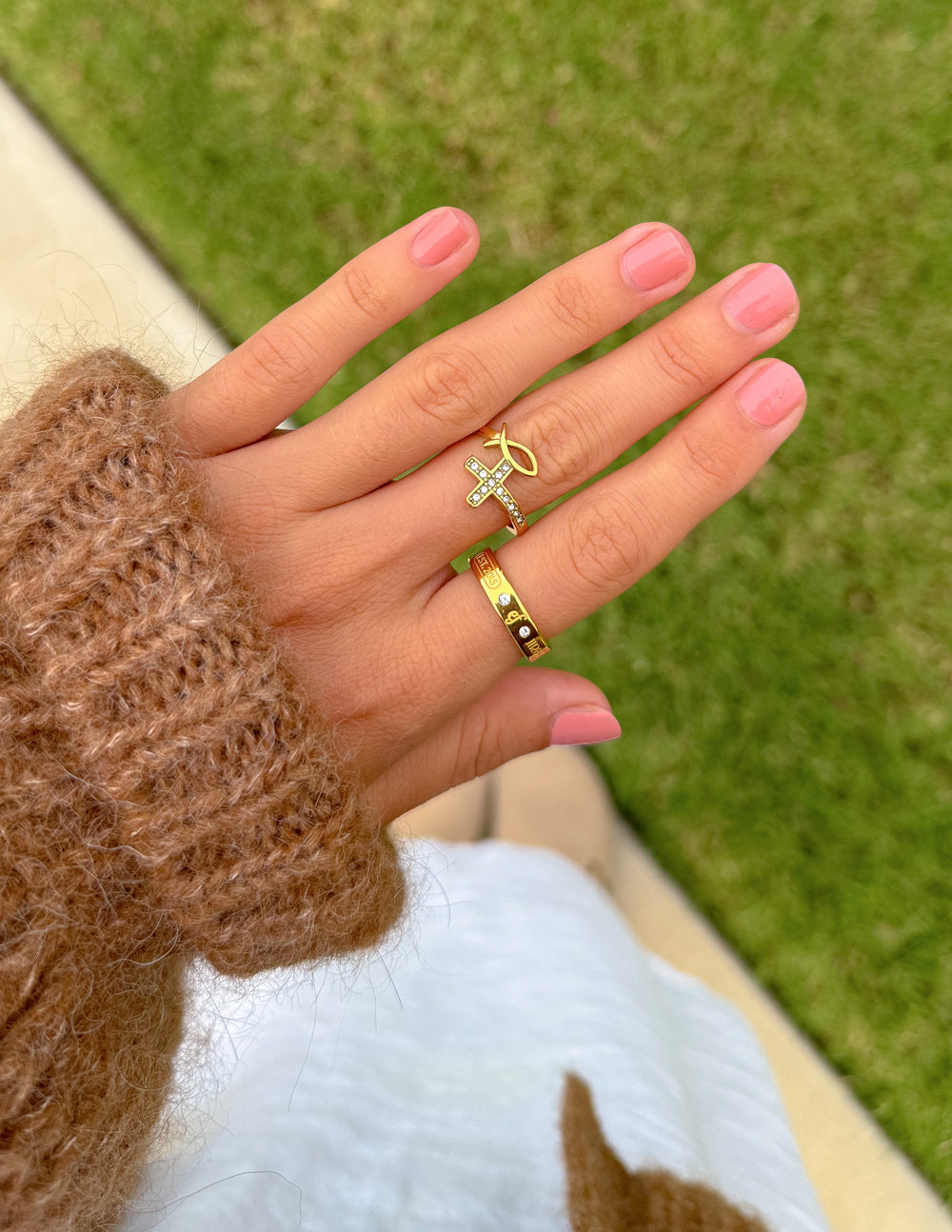 Gold-tone cross motif gemstone ring on finger with slim engraved band