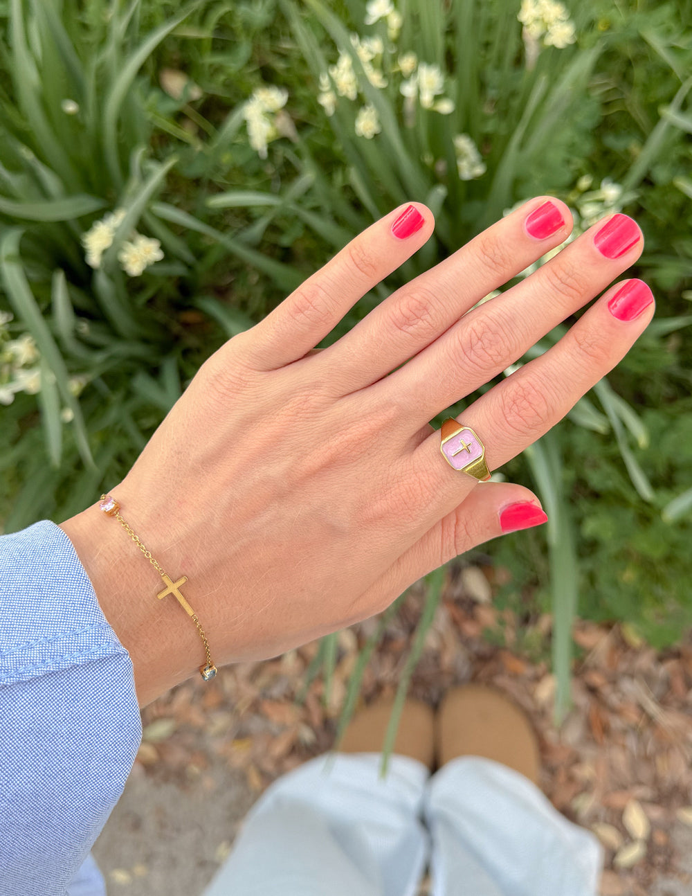 Gold link bracelet with cross charm on wrist, delicate chain and stones