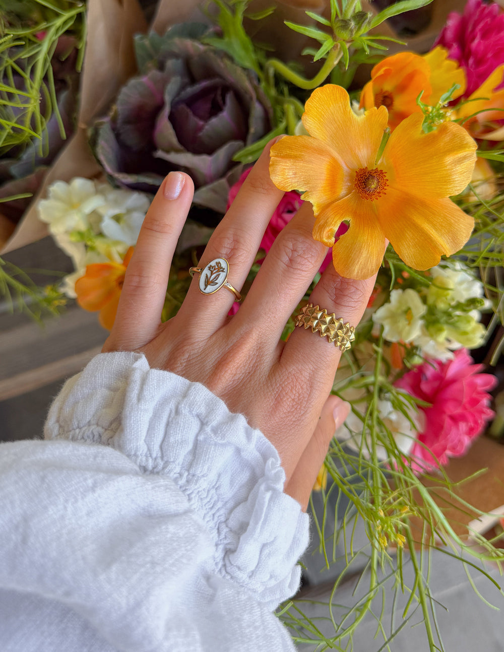 Gold enamel oval floral ring with a tiny stone detail near the setting