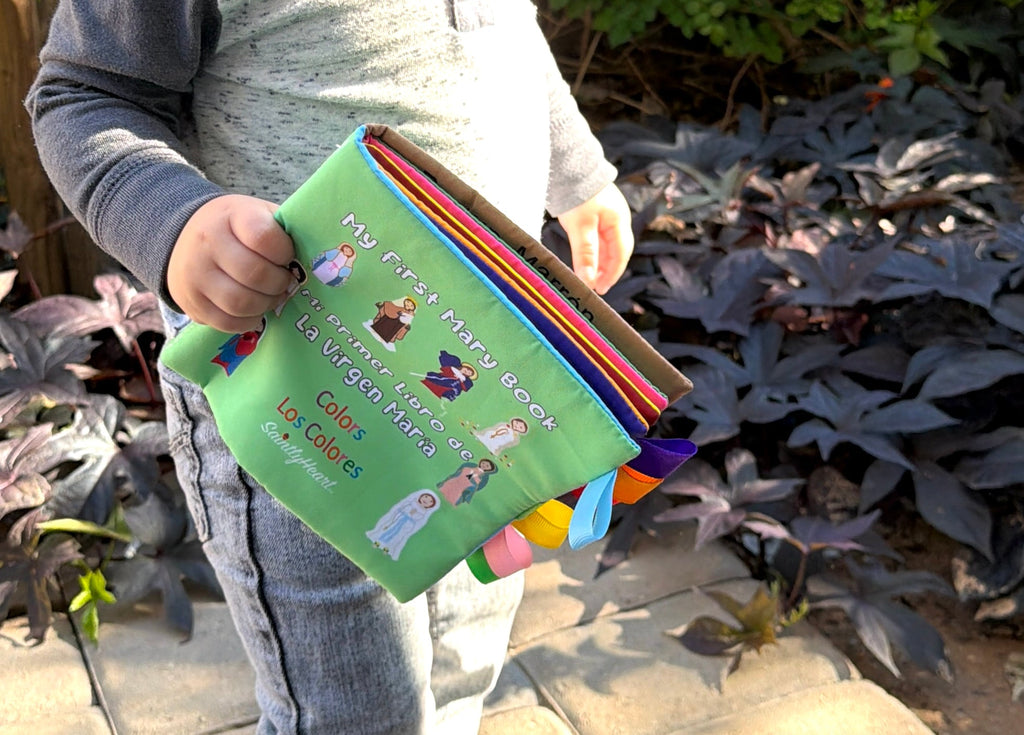 Fabric Mary colors book held by a child, green cover with rainbow fabric edge pages.