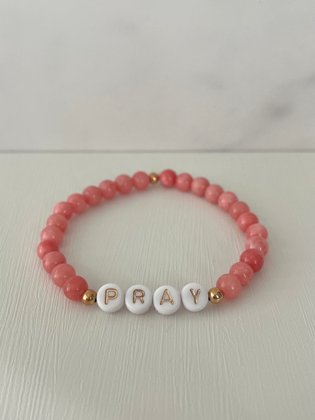 Red beaded bracelet with PRAY letter beads and small gold accent beads