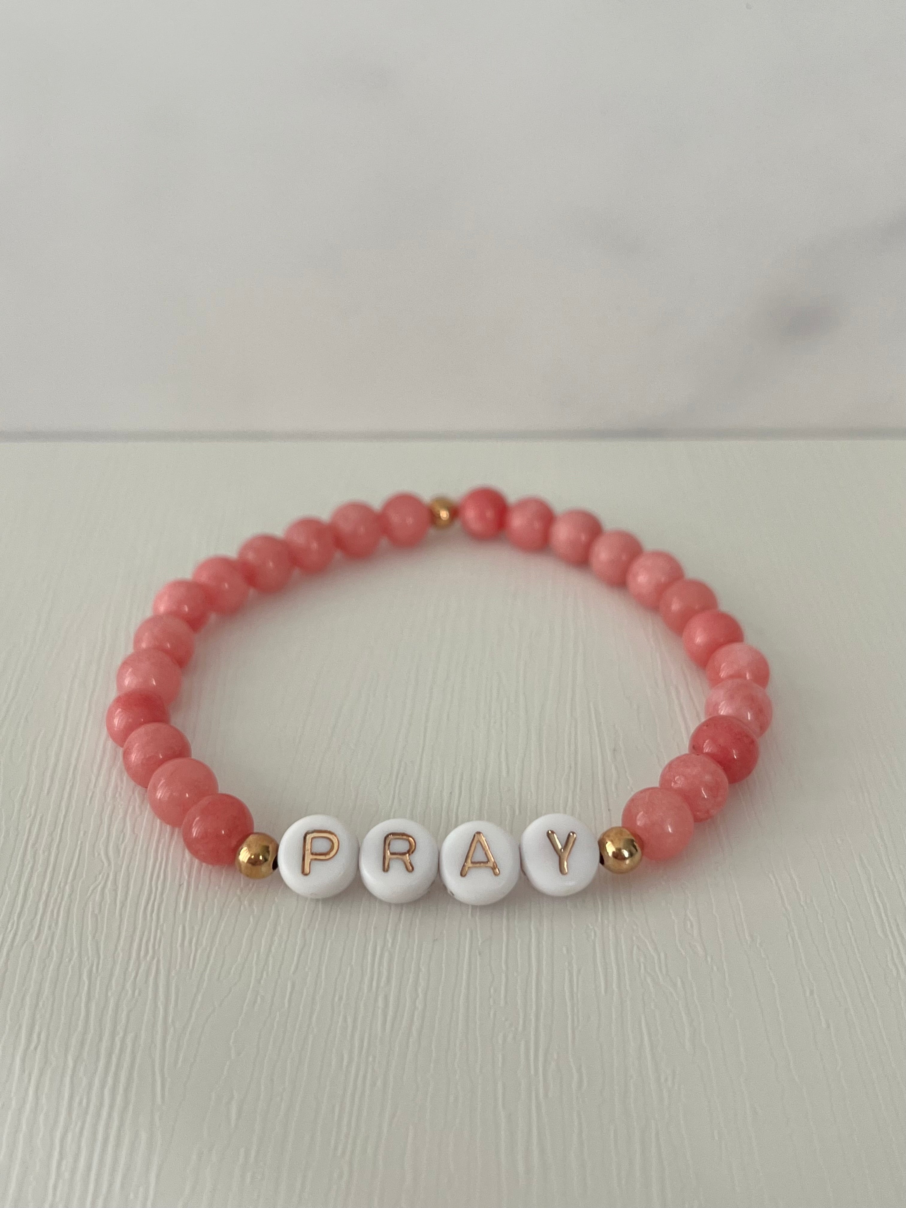 Red beaded bracelet with PRAY letter beads and small gold accent beads