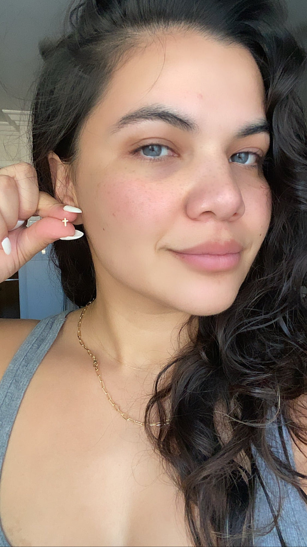 14k gold cross stud earring on ear, small cross charm on a post