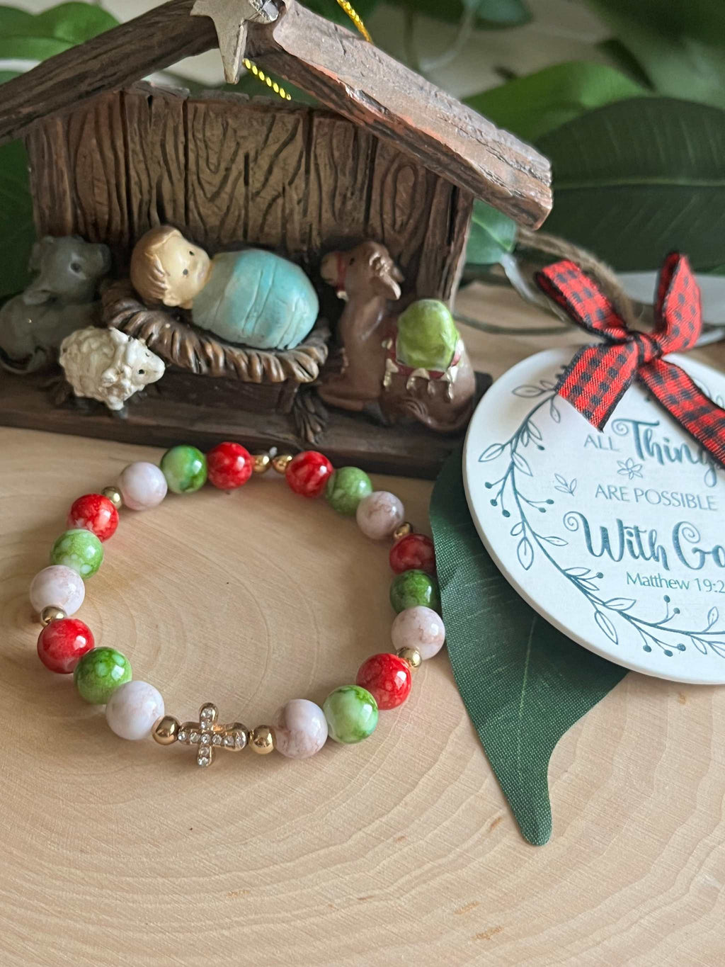 Beaded bracelet with red, green, and white beads and a small silver cross charm