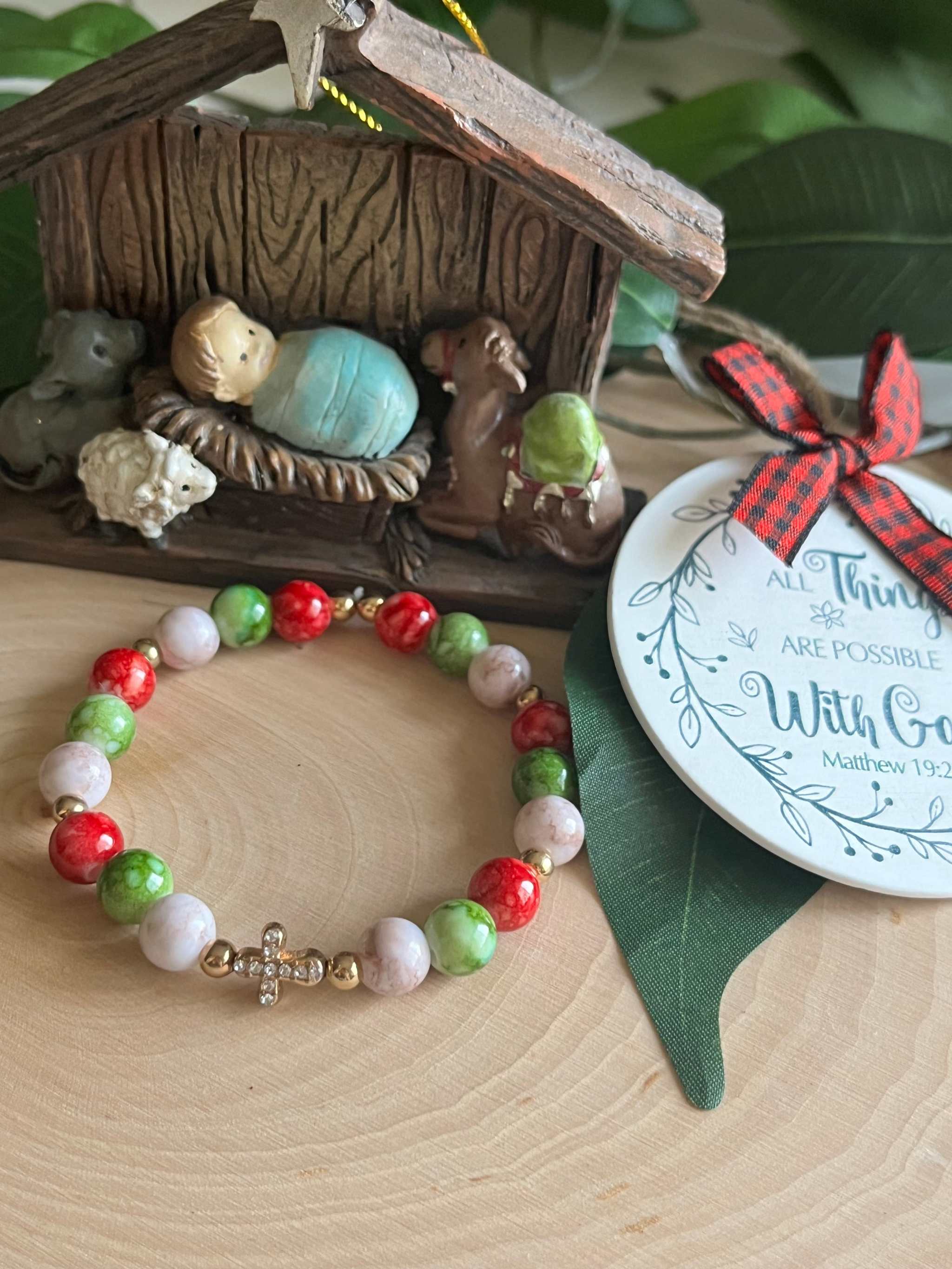 Beaded bracelet with red, green, and white beads and a small silver cross charm