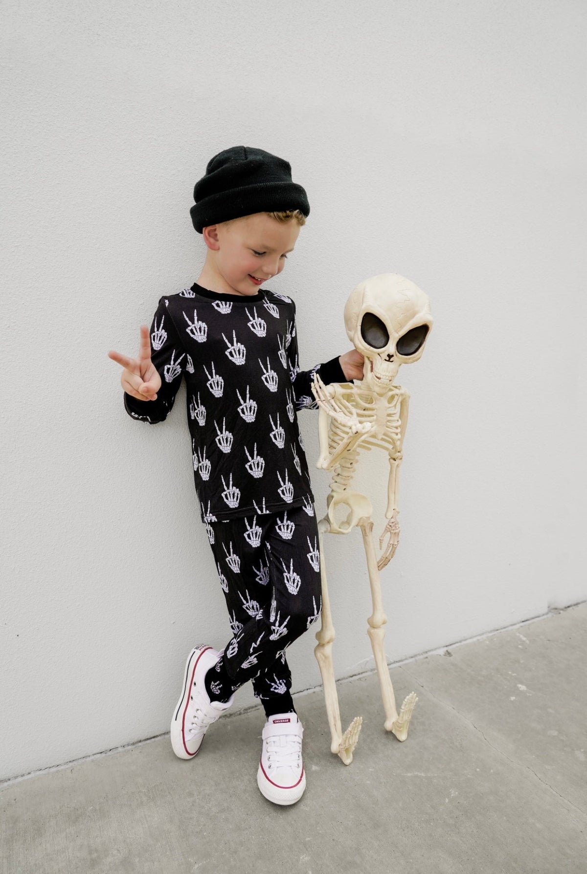 Kids black pajama set with white skeleton-hand print, full-length long sleeves.
