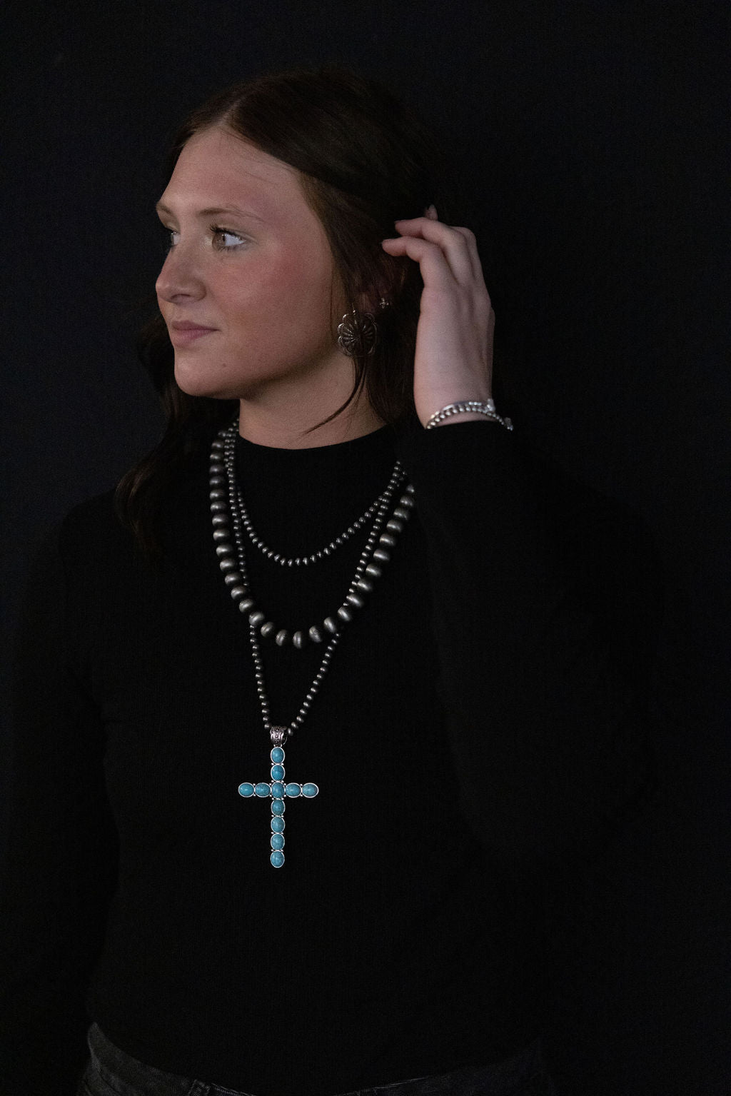 Three-layer cross necklace with dark beaded strands and turquoise cross charm