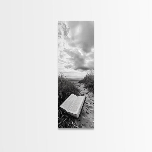 Canvas print of open Bible on a sandy beach path under cloudy sky