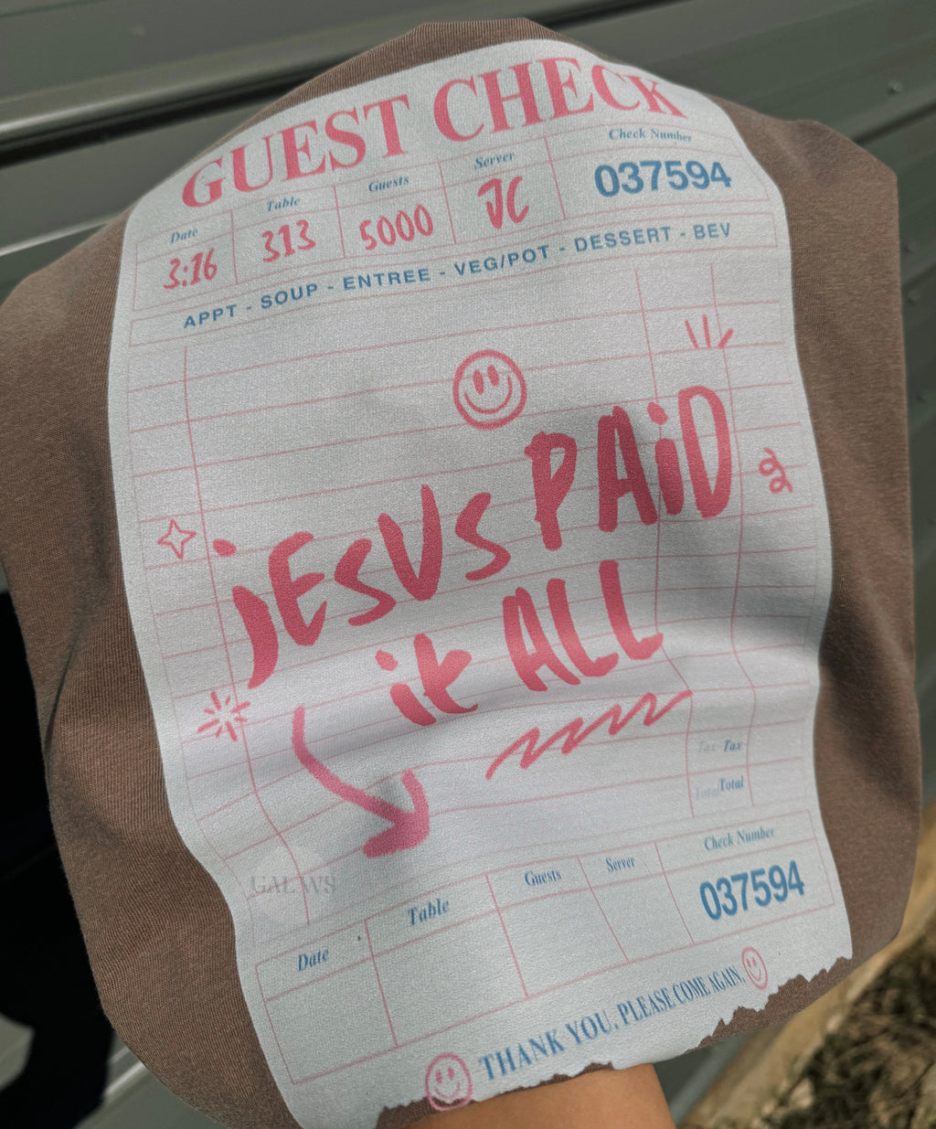 Brown guest check graphic tee with red lettering and 'Jesus paid it all' design