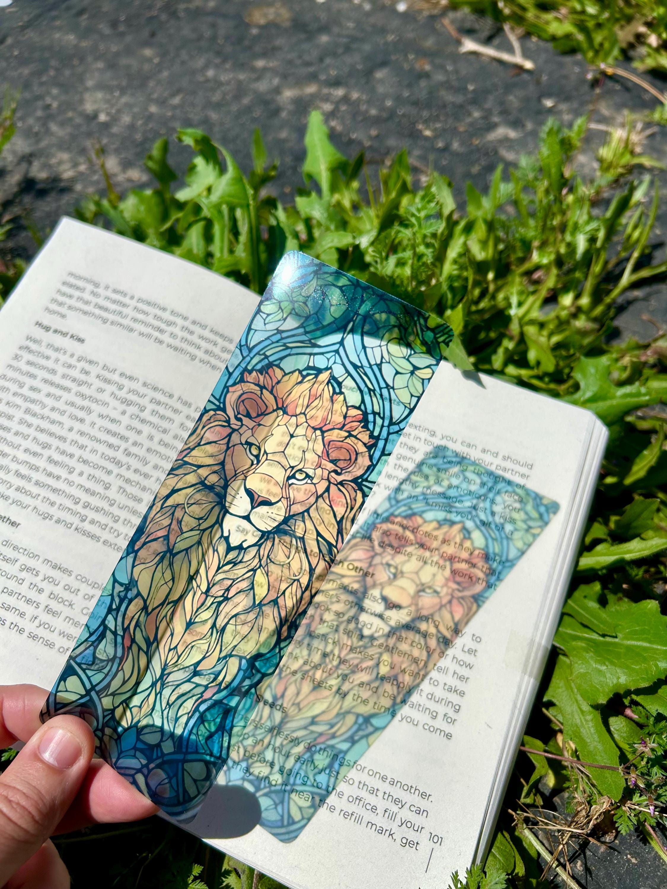 Lion face bookmark in teal with detailed line art, set in an open book