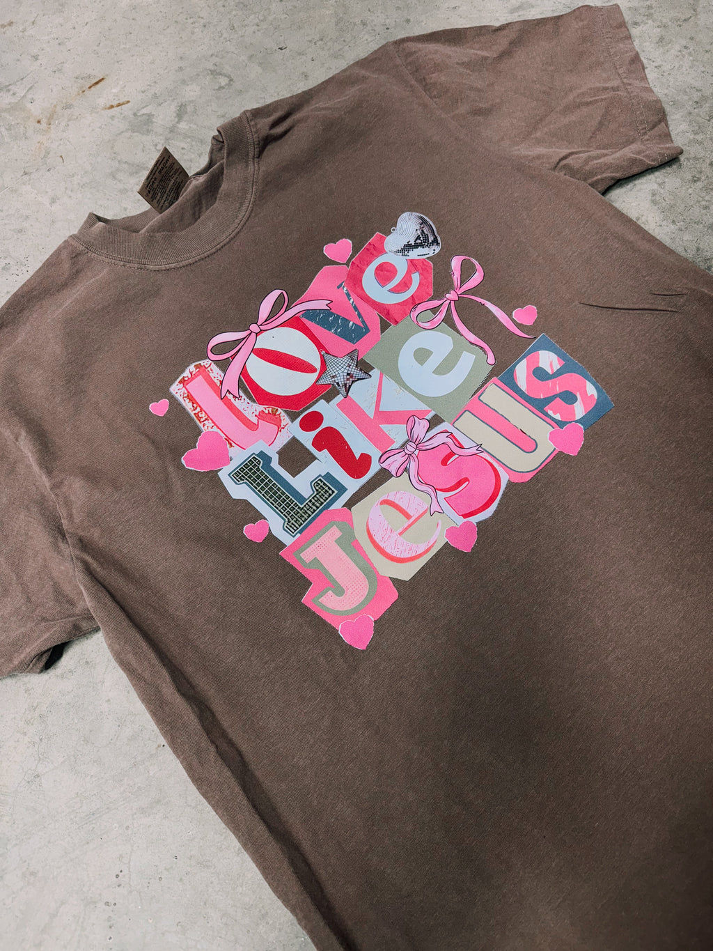 Dark brown short-sleeve graphic T-shirt with 'Love Like Jesus' heart and bow print