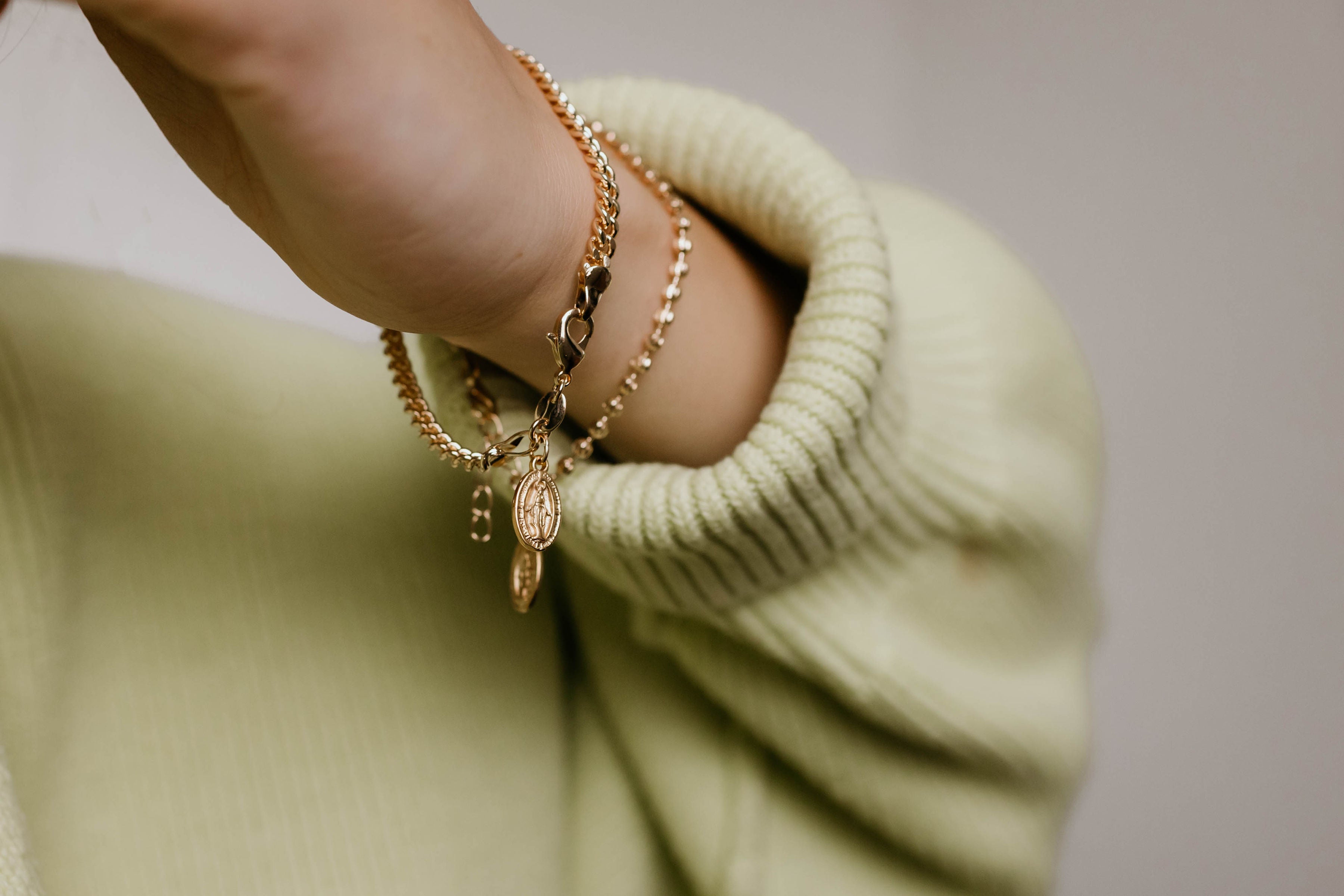 Gold-tone chain bracelet with oval medal charm on wrist
