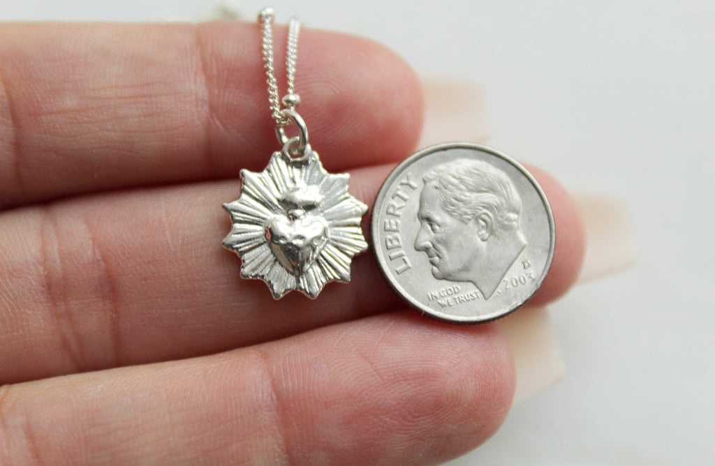 Sterling silver heart pendant necklace next to a quarter coin for size