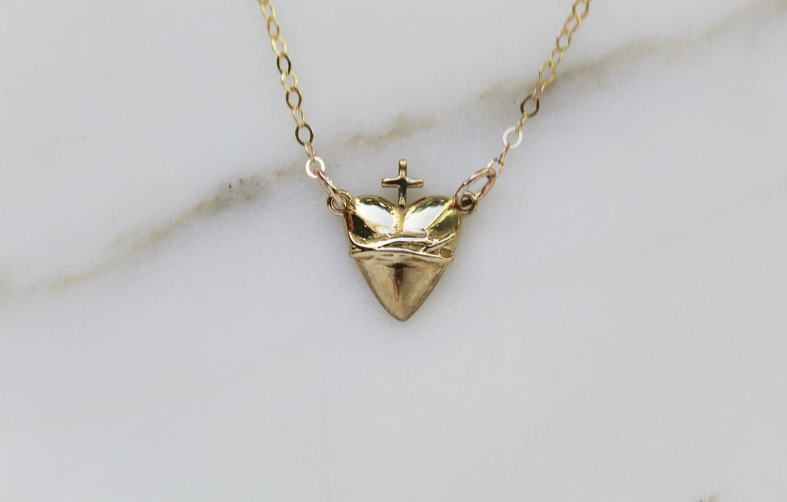 Gold-tone heart pendant necklace with crown and cross centerpiece
