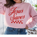 Light pink crewneck sweatshirt with red "Jesus Saves" text and checkered graphic