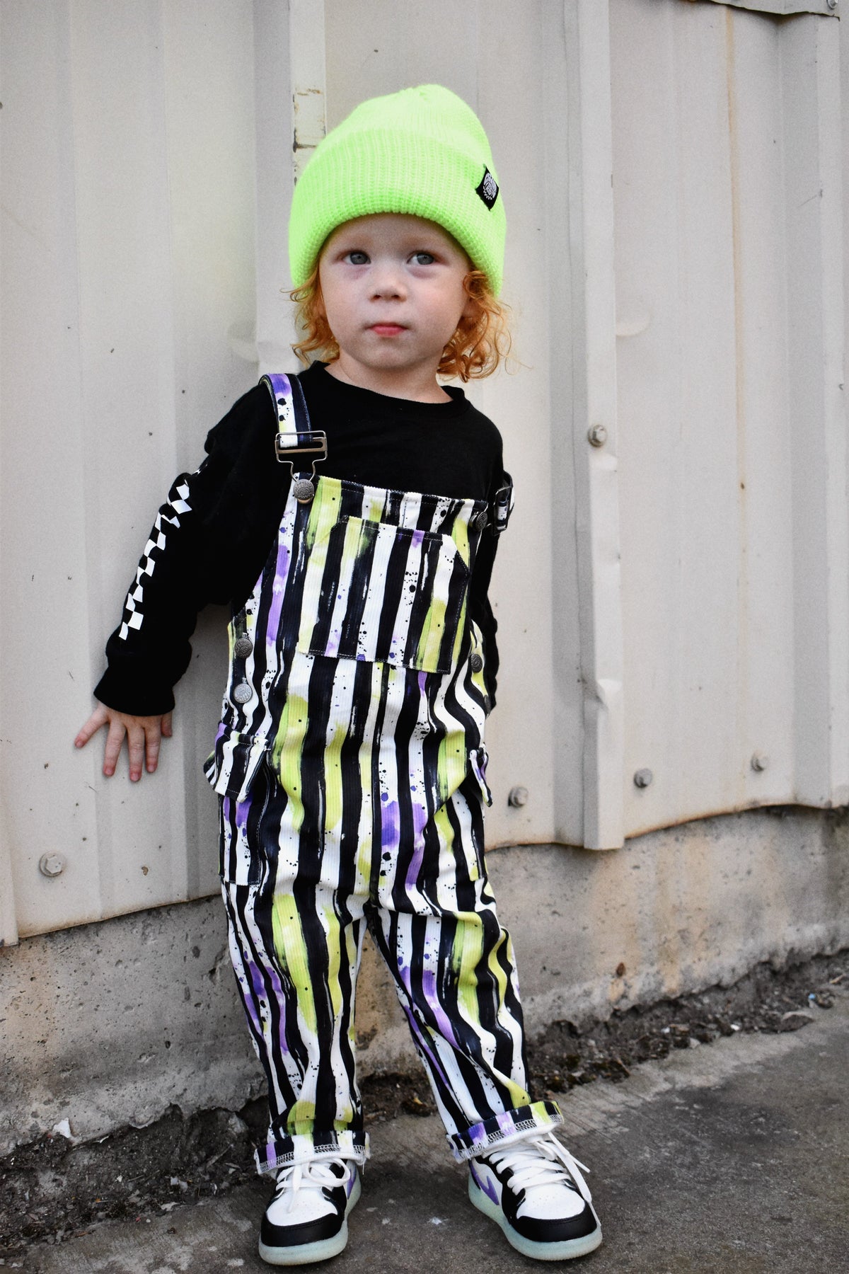 Kids striped Halloween overalls with neon green and purple pattern and shoulder buckles