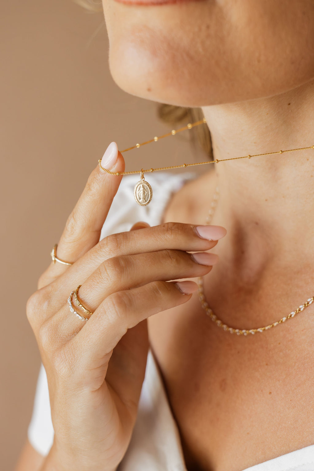Gold chain necklace with oval medal pendant, delicate chain draped on neck