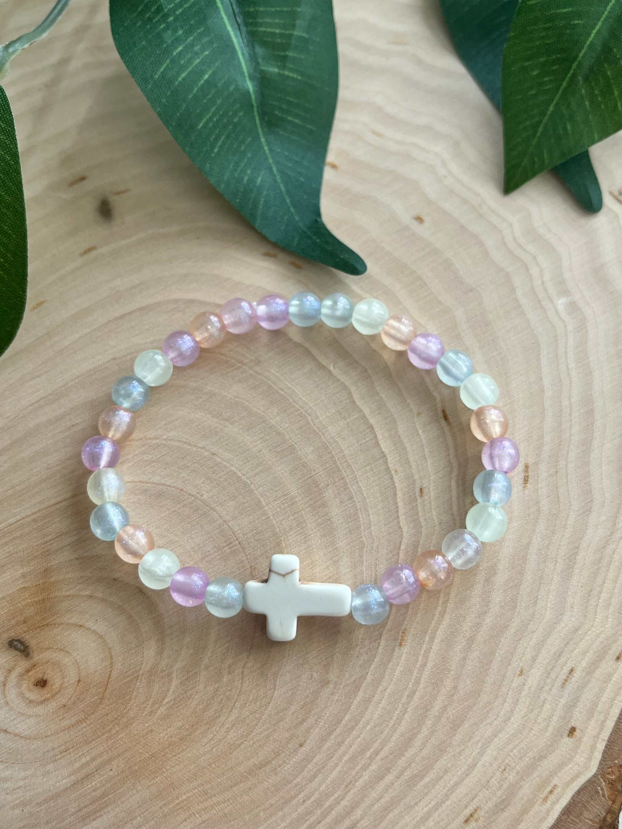 Colorful bead bracelet with a central white cross charm and pastel multicolor beads.