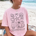 Women's pink Christian graphic T-shirt with seashell artwork and 'Colossians 1:16' text