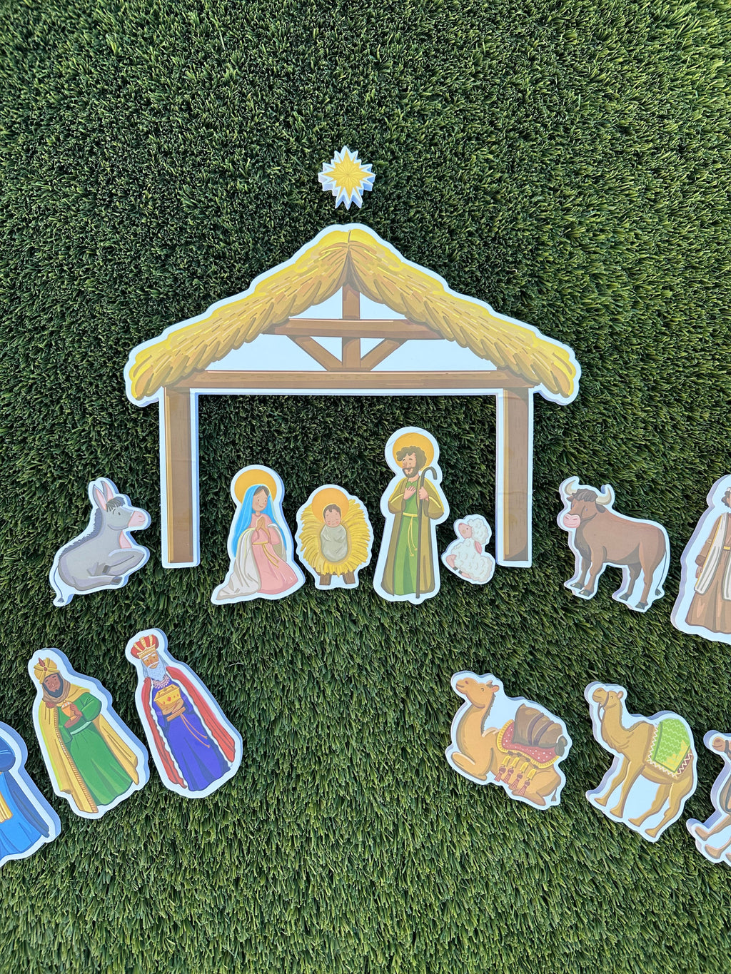 Nativity bath toy stable with people and animal cutouts arranged on green mat