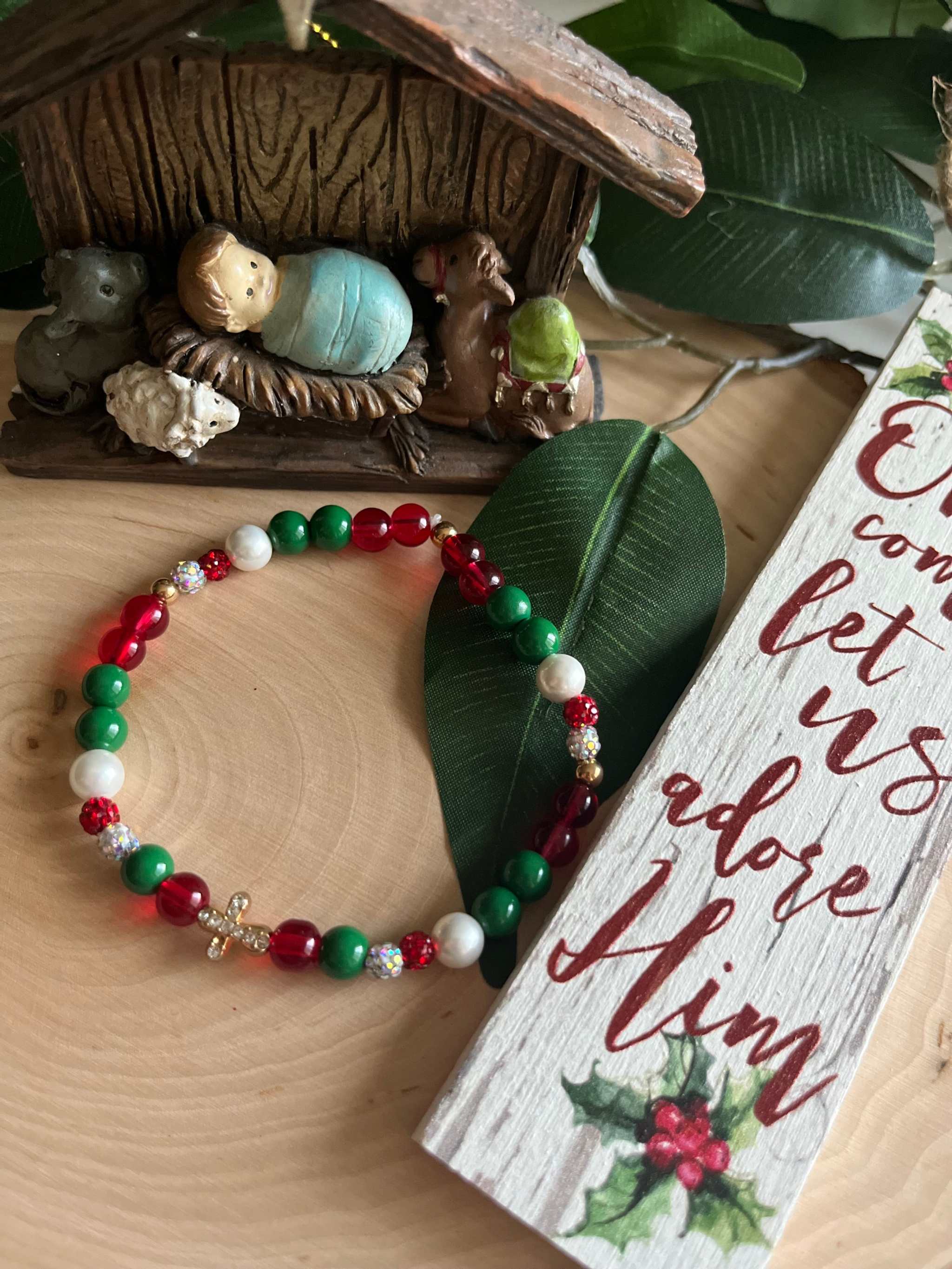 Beaded bracelet with red, green, and white beads and a small silver cross charm