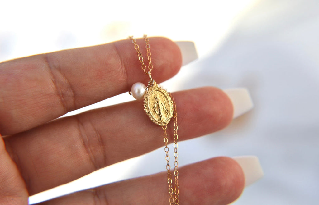 Gold-tone medal necklace with pearl bead and oval filigree pendant on delicate chain